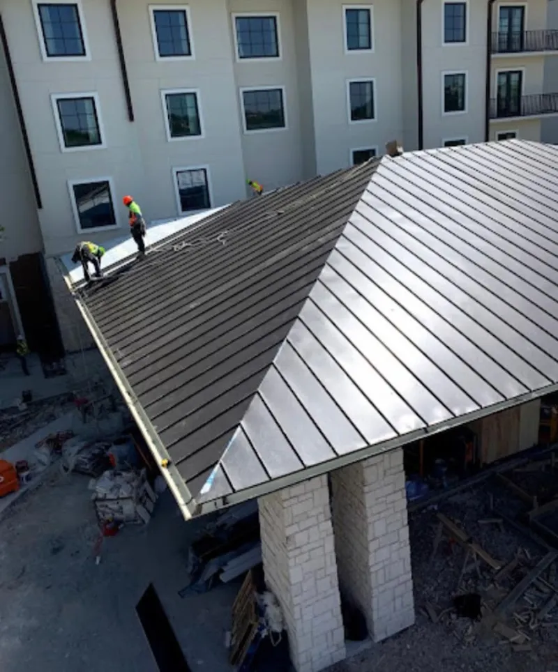 Crew installing standing seam metal roof panels on a commercial project in Dormont